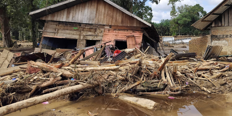 Tree trunks and debris lie in front of a damaged house in an area hit by deadly flash floods following heavy rains in Batang Toru, South Tapanuli, North Sumatra, Indonesia, November 29, 2025. REUTERS/Arif Nasution