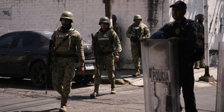 Soldiers patrol a residential area after police and army soldiers seized lumber from a warehouse in the Iztacalco borough of Mexico City, Tuesday, April 1, 2025. (AP Photo/Marco Ugarte)