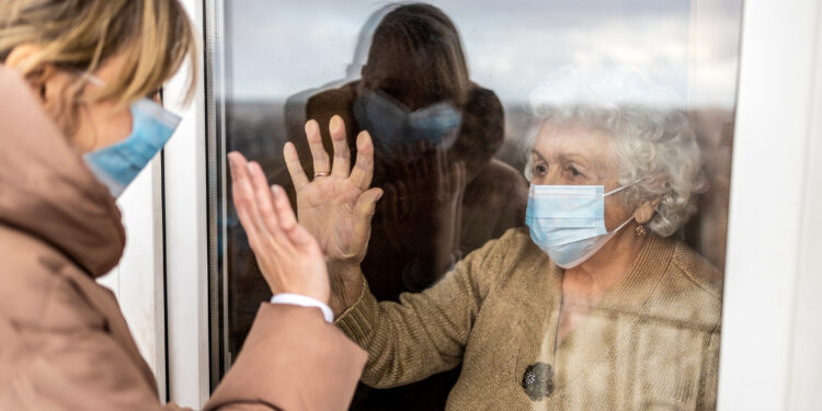 Woman visiting her grandmother in isolation during a coronavirus pandemic