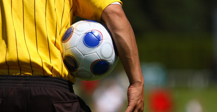 A soccer referee holding a soccer ball.
